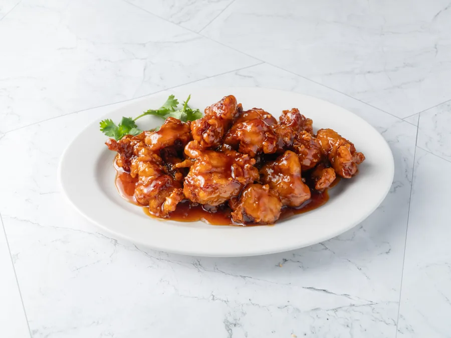 Glossy orange chicken with a sprig of cilantro