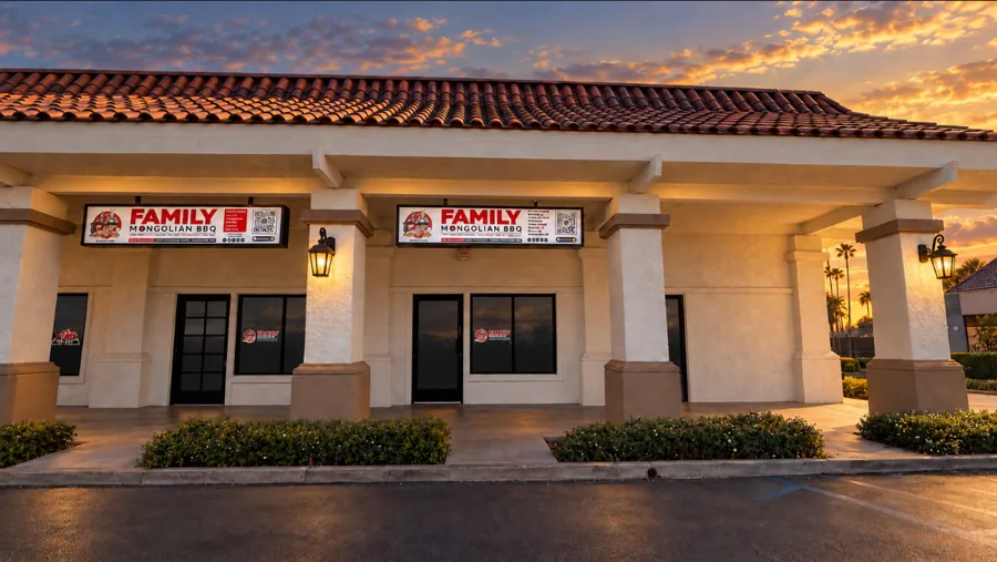 Family Mongolian BBQ storefront at dusk: tile roof, arched columns, lit wall lanterns and the red FAMILY MONGOLIAN BBQ sign
