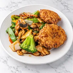 Two egg foo young patties beside stir-fried chicken and vegetables