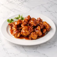 Orange chicken with a sprig of cilantro