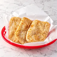 Three sesame pocket breads in a red basket
